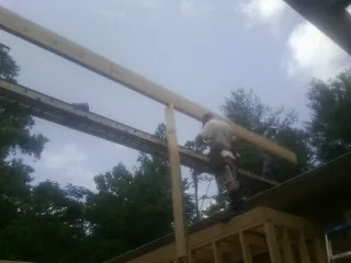 Carpenter setting a ridge beam over a new addition frame — Ice Dam Removal by Roofing Brothers in Turbeville