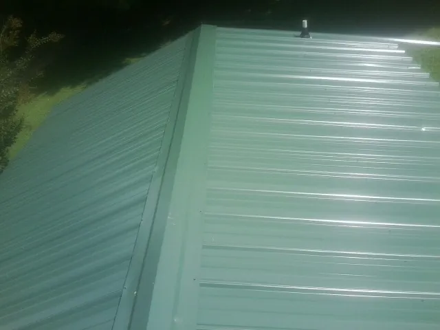 New green metal panels meeting at the ridge of a roof — Flat Roof Repair work by our crew in Turbeville