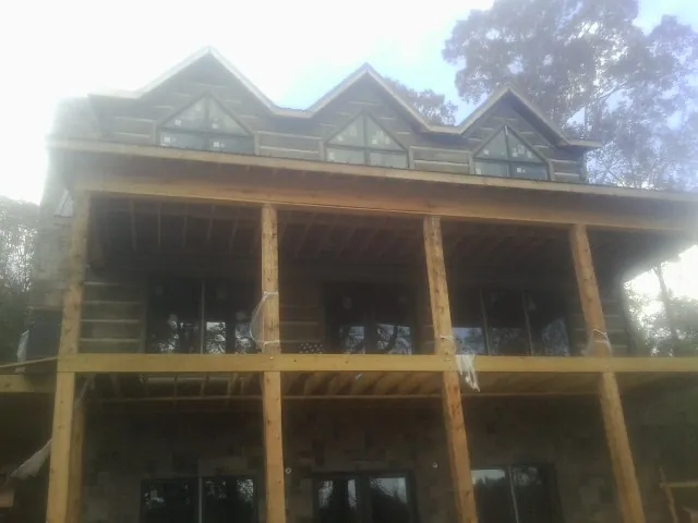 Dormers and porch framing on a large log home under construction — Roof Coating work by our crew in Turbeville