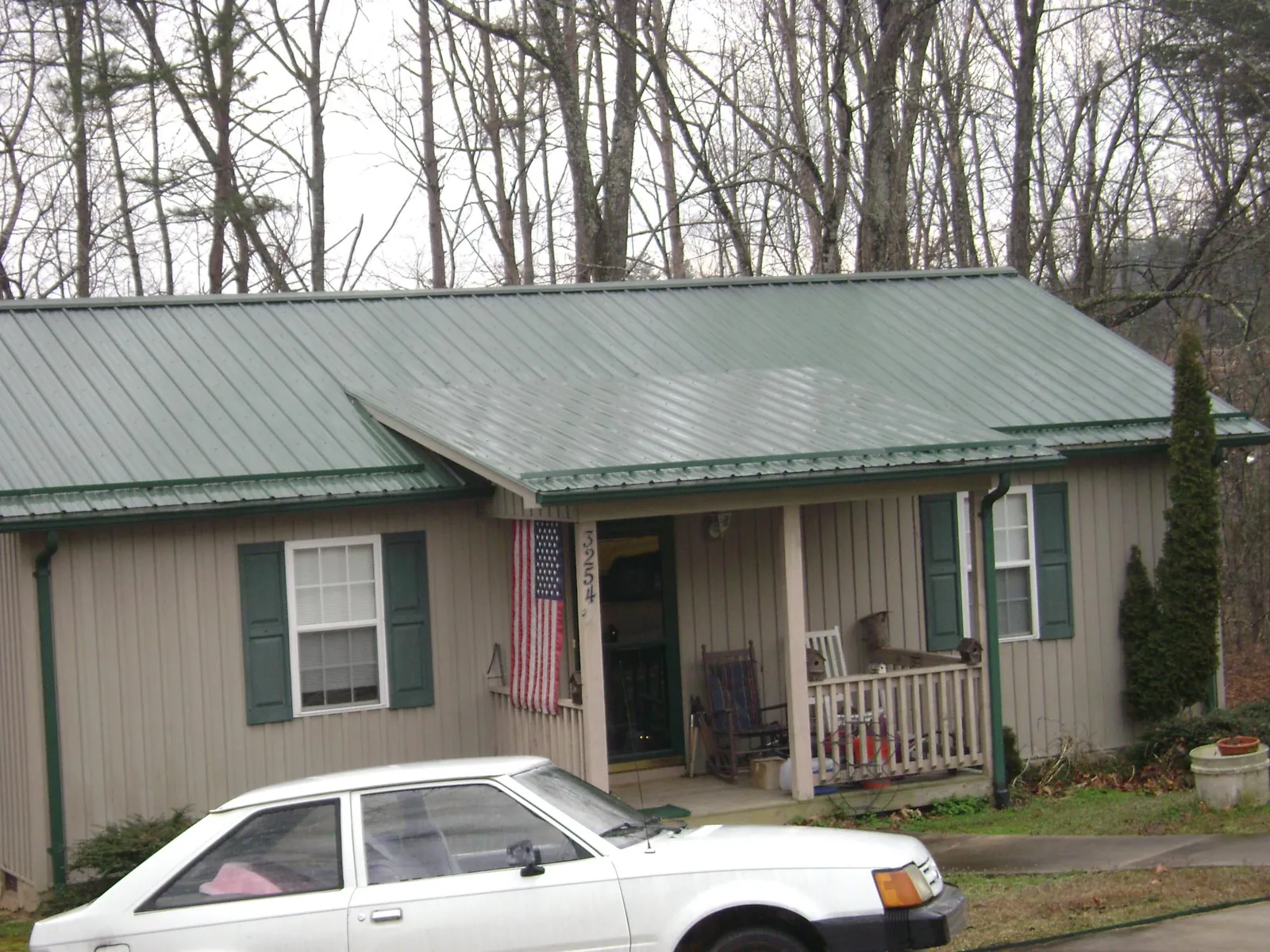 Green metal roof and front porch on a tan sided cottage in Turbeville