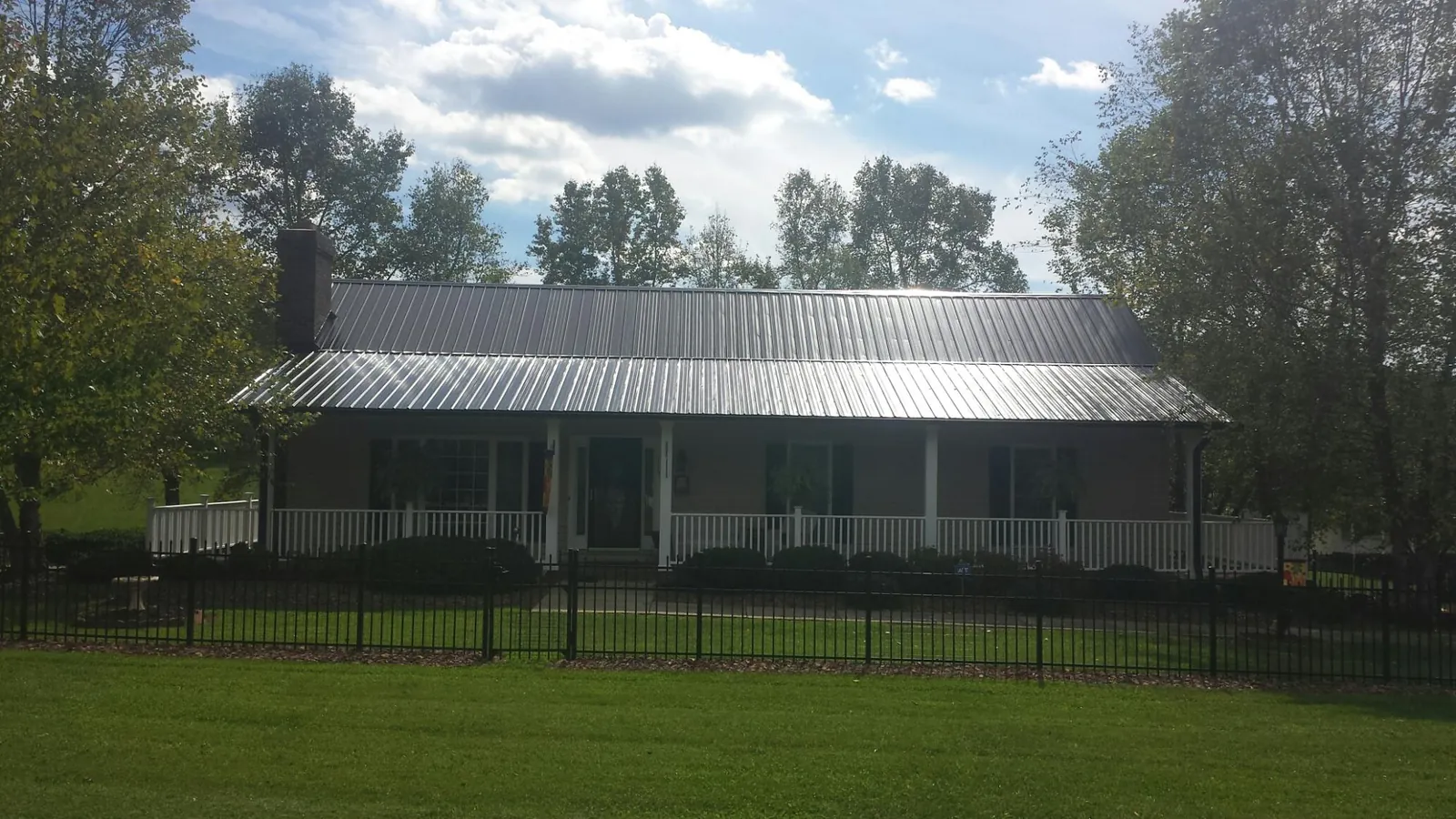 Gray metal roof on a brick ranch with a full width front porch — Gutter Guard Installation work by our crew in Turbeville