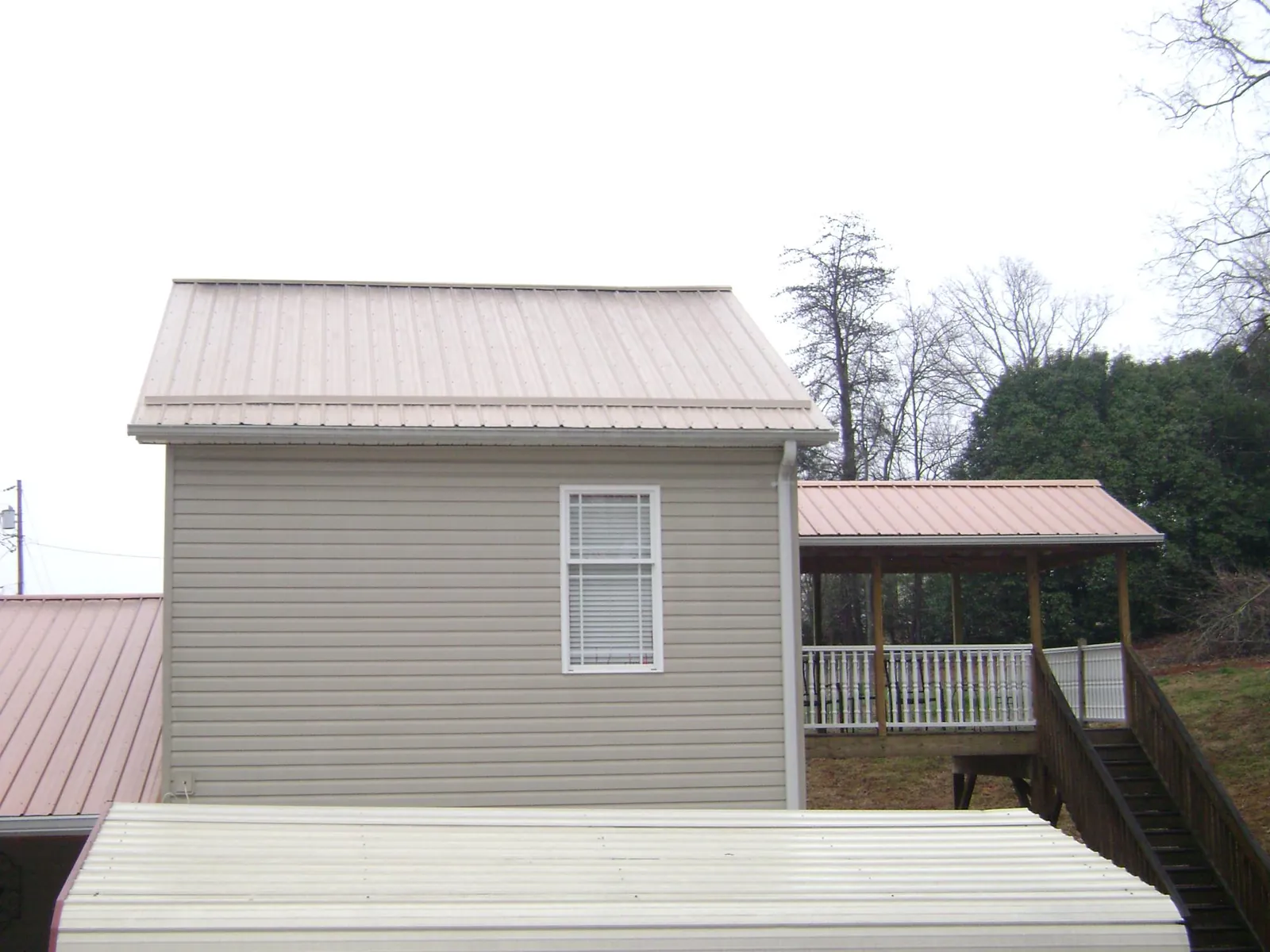 Tan metal roofs on a two story addition and attached porch, from a Roof Replacement job in Turbeville