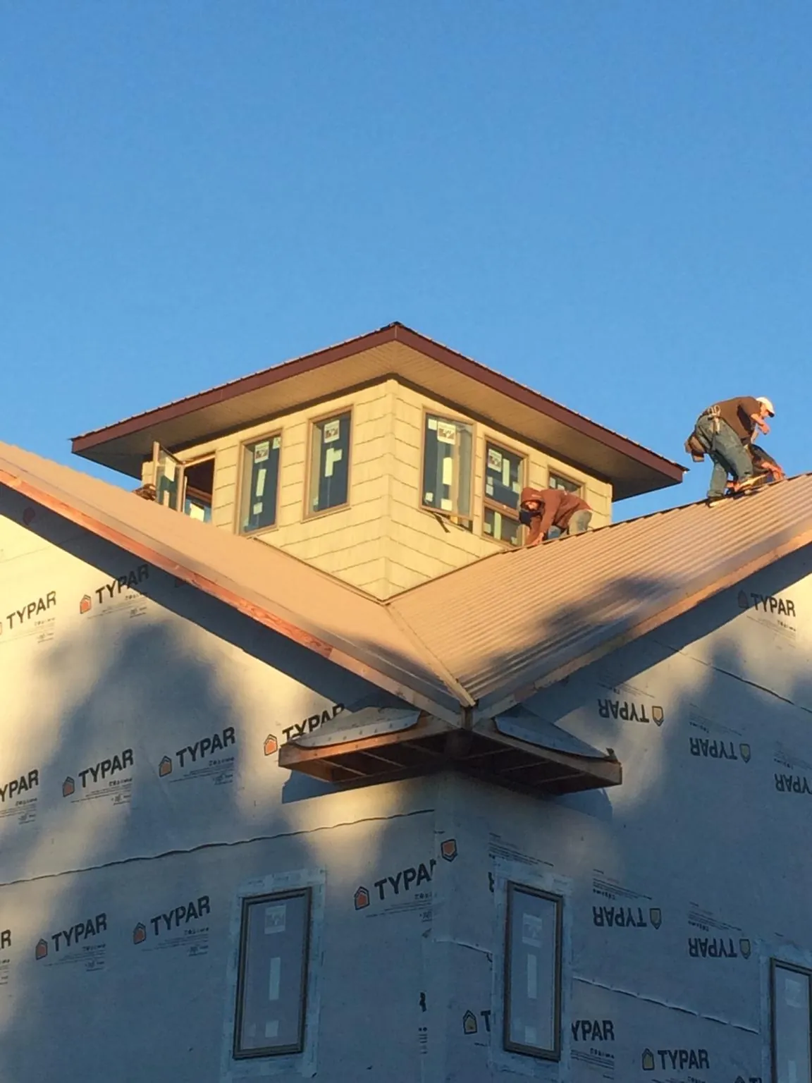 Roofers working around a rooftop cupola on a new metal roof at sunset — Roof Waterproofing in Turbeville by Roofing Brothers